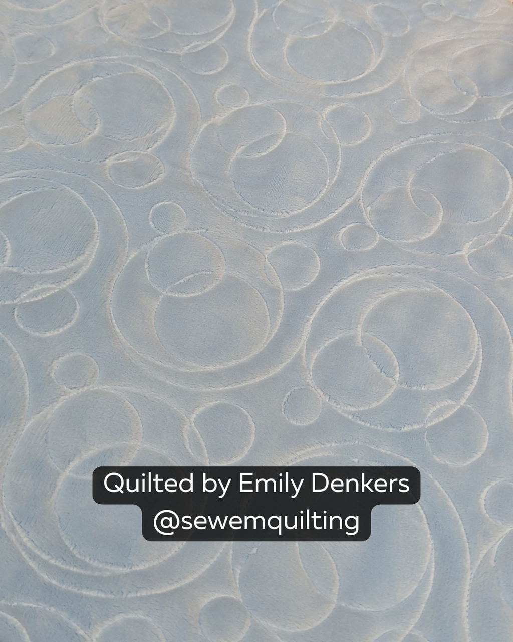 Close-up of a soft white quilt featuring the Fizz bubble quilting pantograph, with playful circles, loops, and swirls stitched edge to edge.