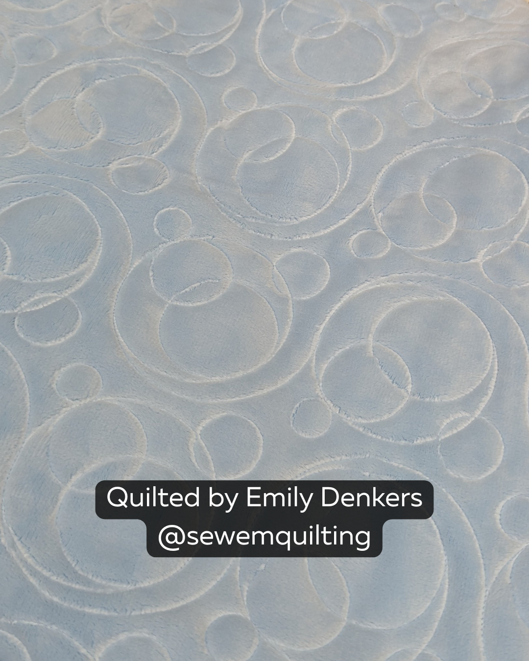 Close-up of a soft white quilt featuring the Fizz bubble quilting pantograph, with playful circles, loops, and swirls stitched edge to edge.