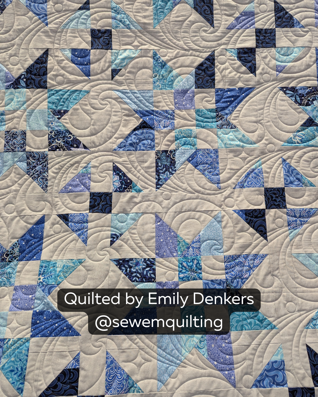 Finished blue and white patchwork quilt featuring the Glittered Paint Pour digital quilting pantograph with flowing abstract swirls and artistic texture
