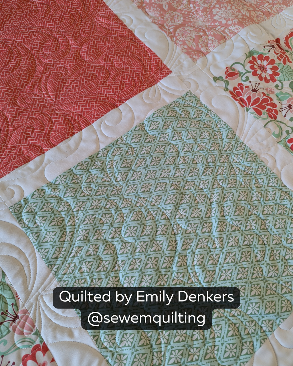 Finished red, green, pink and white patchwork quilt featuring the Jubilee feather quilting pantograph, with graceful swirls and feather shapes stitched edge to edge.