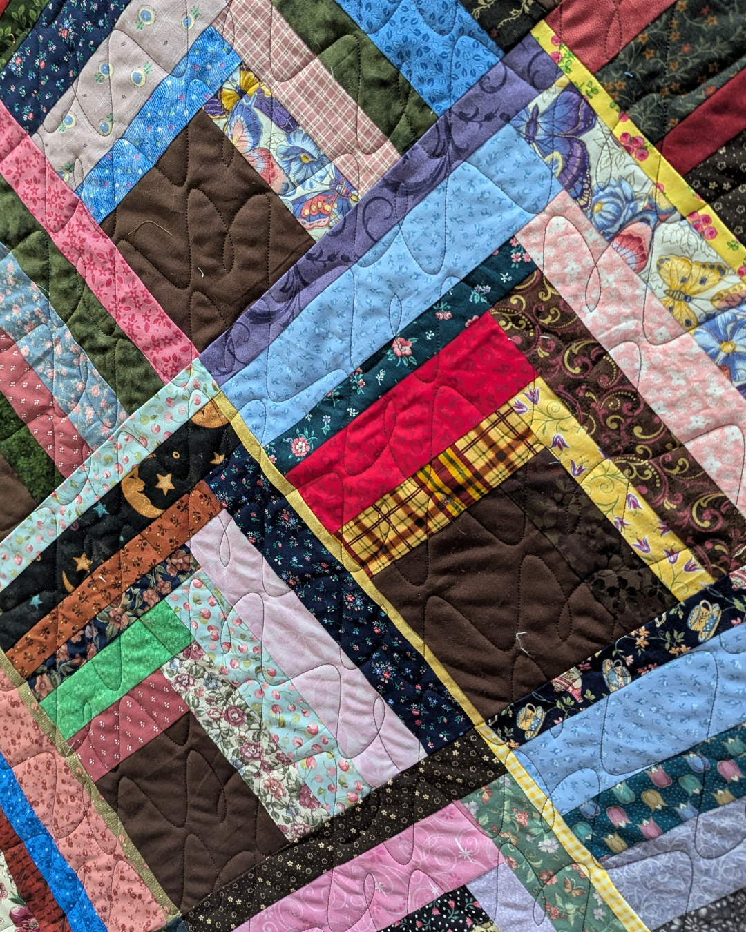 Finished colorful scrap quilt featuring the Loopy Argyle quilting pantograph, with smooth looping geometric shapes stitched edge to edge across mixed fabric blocks.