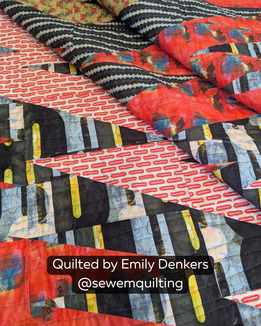 "Finished quilt example using the Organic Extended Width minimalist pantograph, showing smooth wavy line stitching draped across a bold red and black abstract-print modern quilt, quilted by Emily Denkers @sewemquilting"