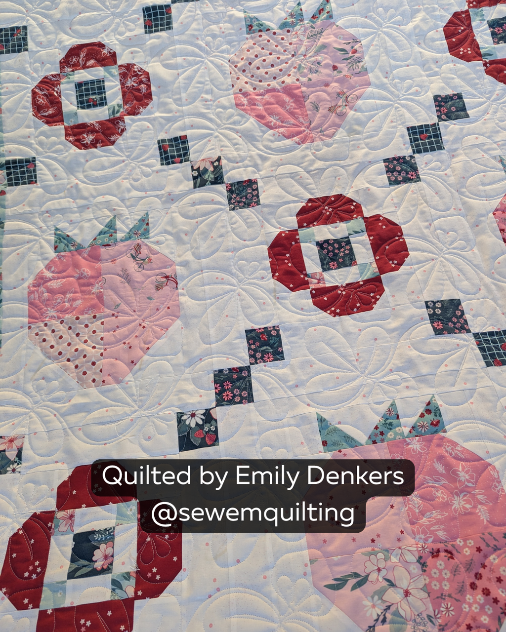 Finished strawberry quilt featuring the Summer Strawberries quilting pantograph, with playful fruit motifs stitched edge-to-edge across pink, red, and floral quilt blocks.