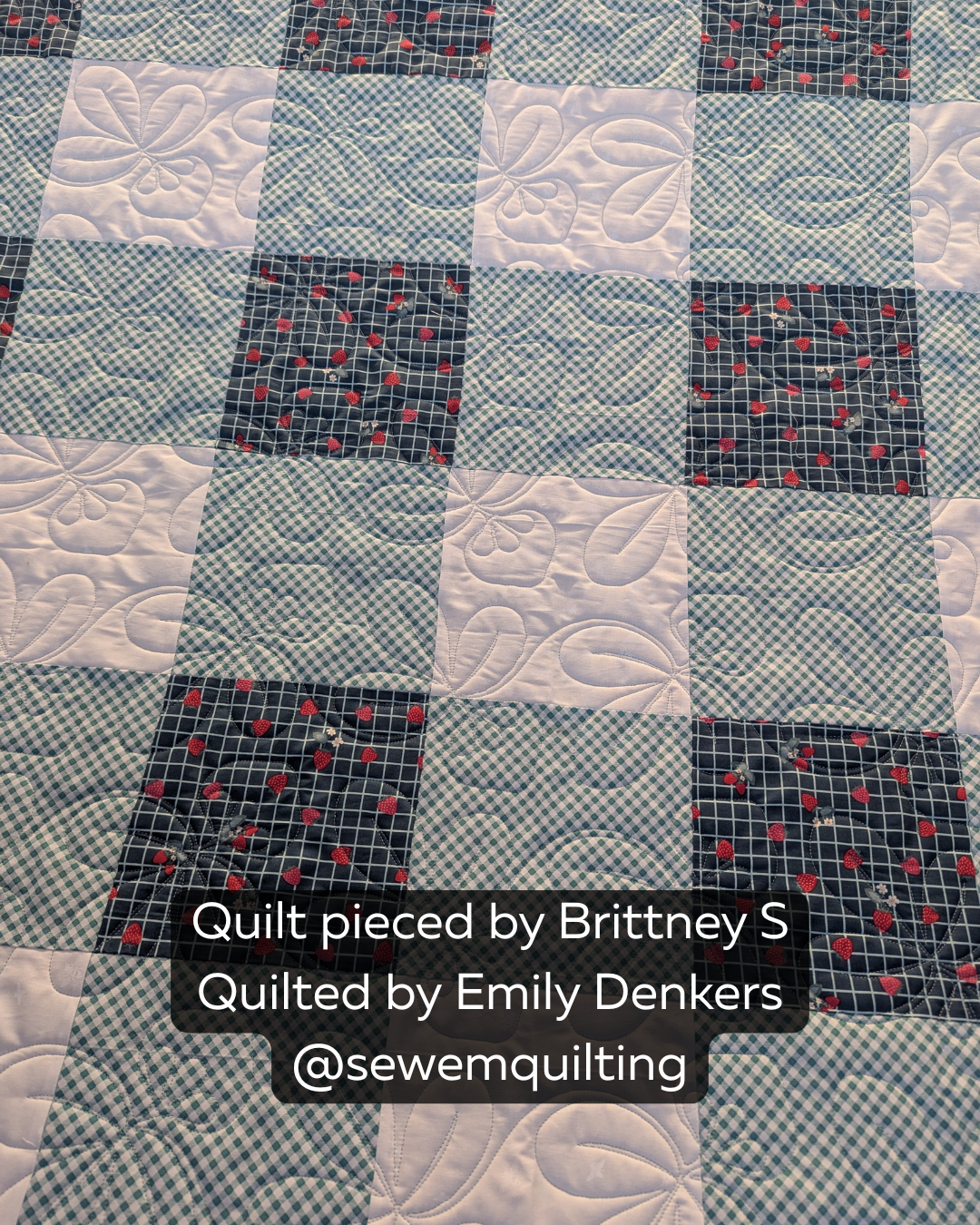 Close-up of a modern quilt with strawberry print fabrics, gingham accents, and elegant edge-to-edge quilting created with the Summer Strawberries quilting pattern