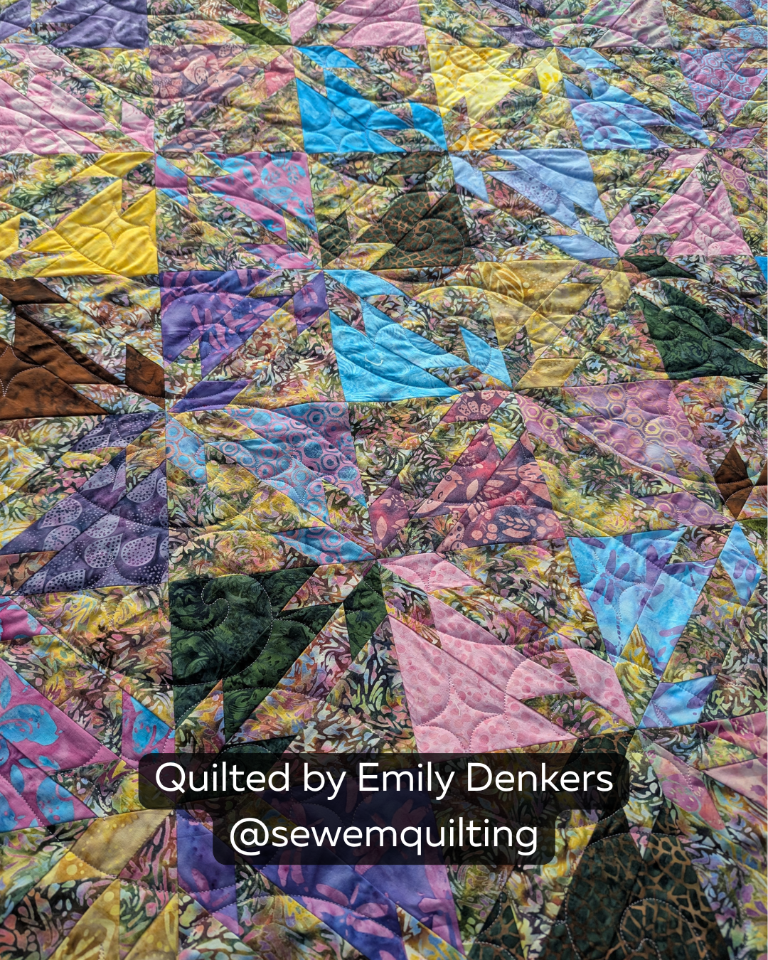 "Finished quilt example using the Swirly Night swirl pantograph, showing flowing swirl stitching on a colorful batik triangle quilt, quilted by Emily Denkers @sewemquilting"