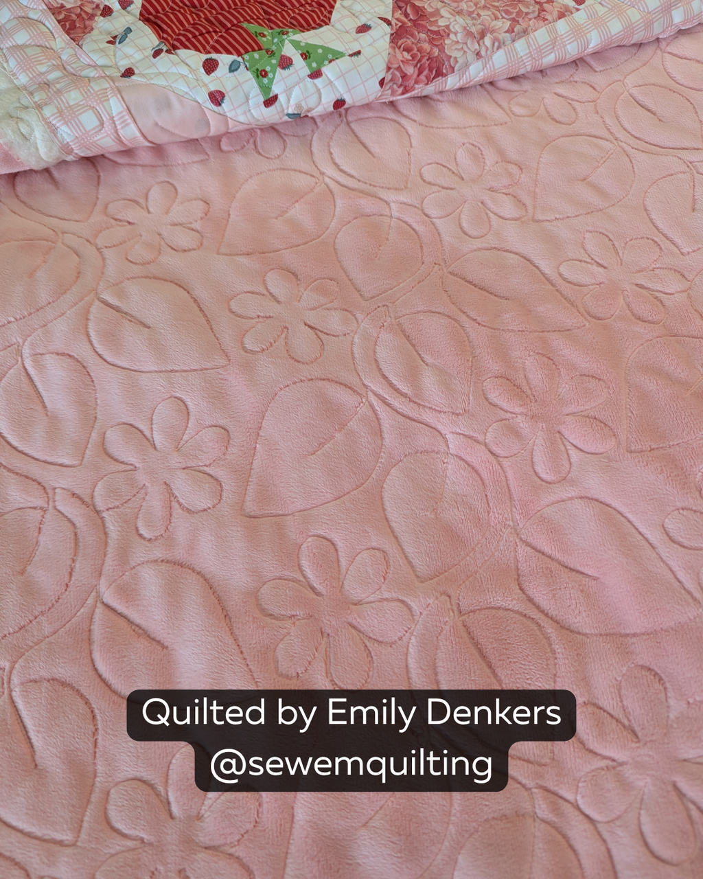 Close-up of a soft pink quilt featuring the Trailing Vine quilting pantograph, with flowing leaves and simple flower motifs stitched edge to edge.